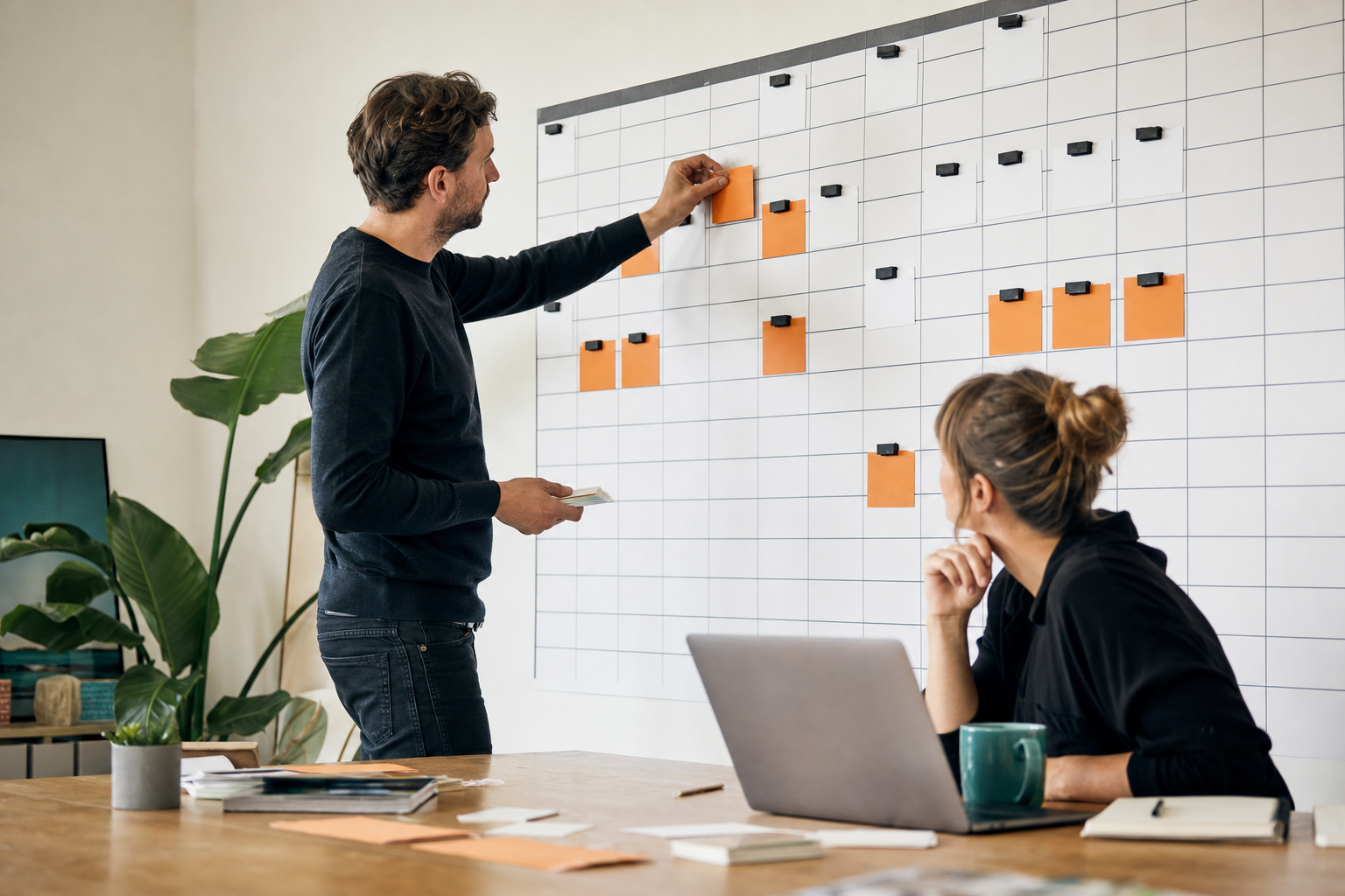Communicatieprofessionals plannen budgetprioriteiten met oranje kaarten op een grote wandplanner